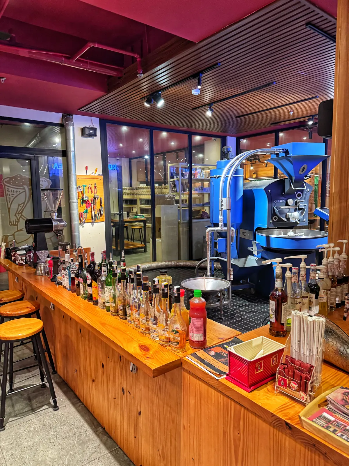 Blue coffee roaster behind a counter with rows of bottles and glass walls