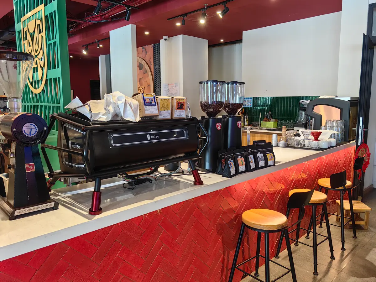 Espresso machine and grinders on a red-tiled counter with bar stools
