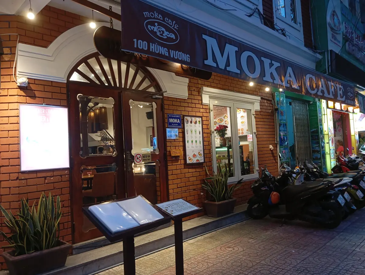 Brick-fronted Moka cafe entrance with a sign, menu stands and parked scooters