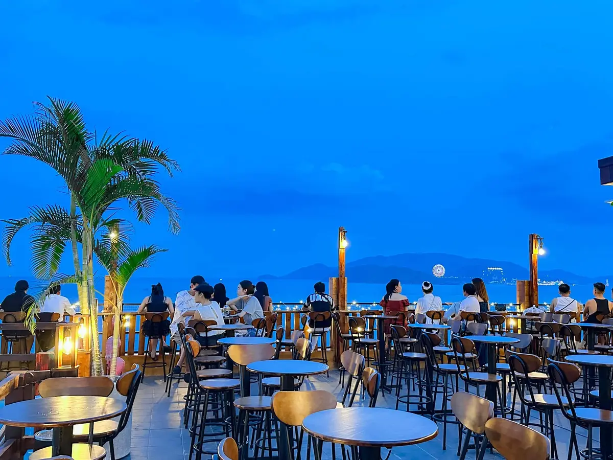 Rooftop terrace at dusk with round tables and chairs looking over the bay