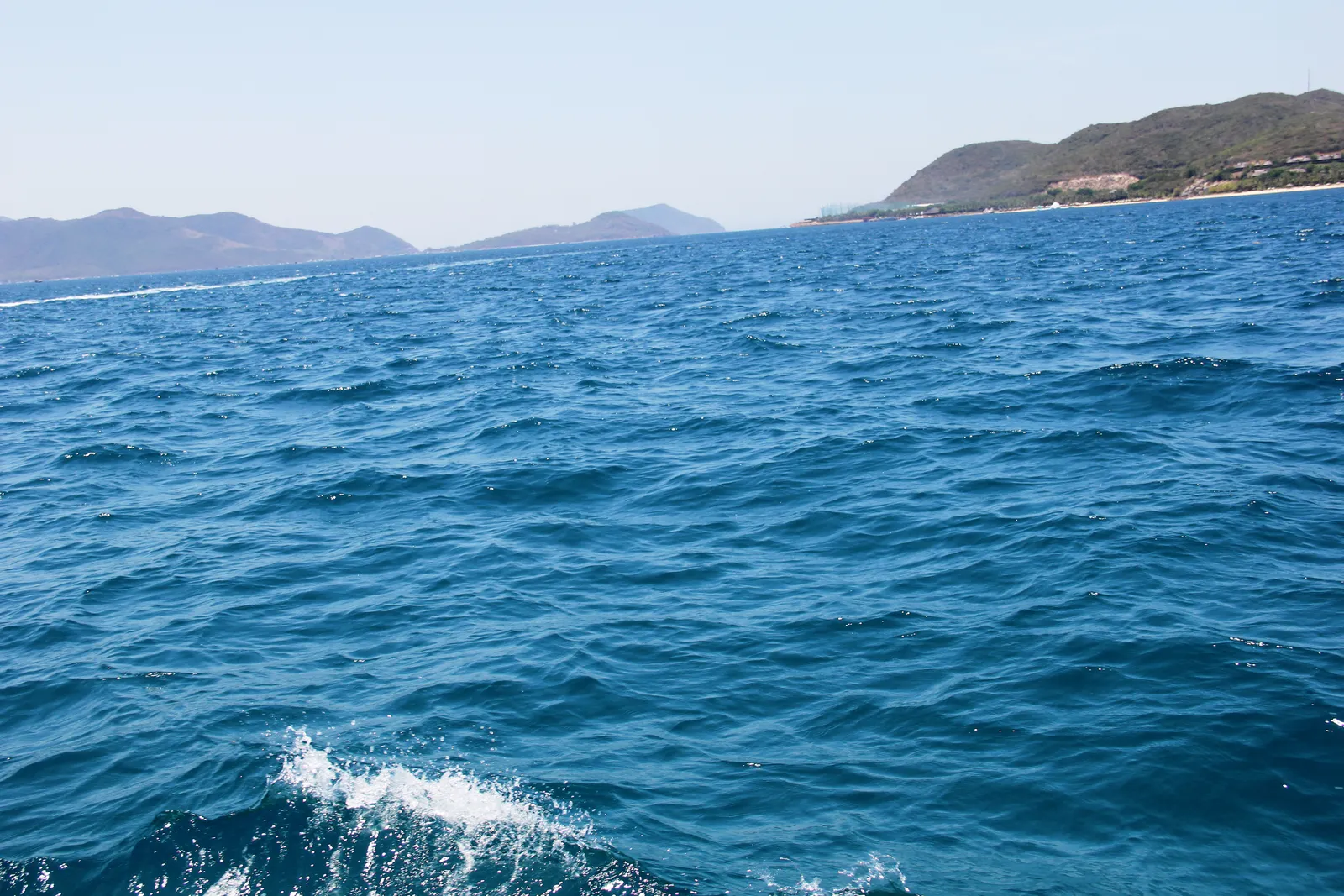 Blue sea off the Nha Trang coast with waves in the foreground and hills on the horizon