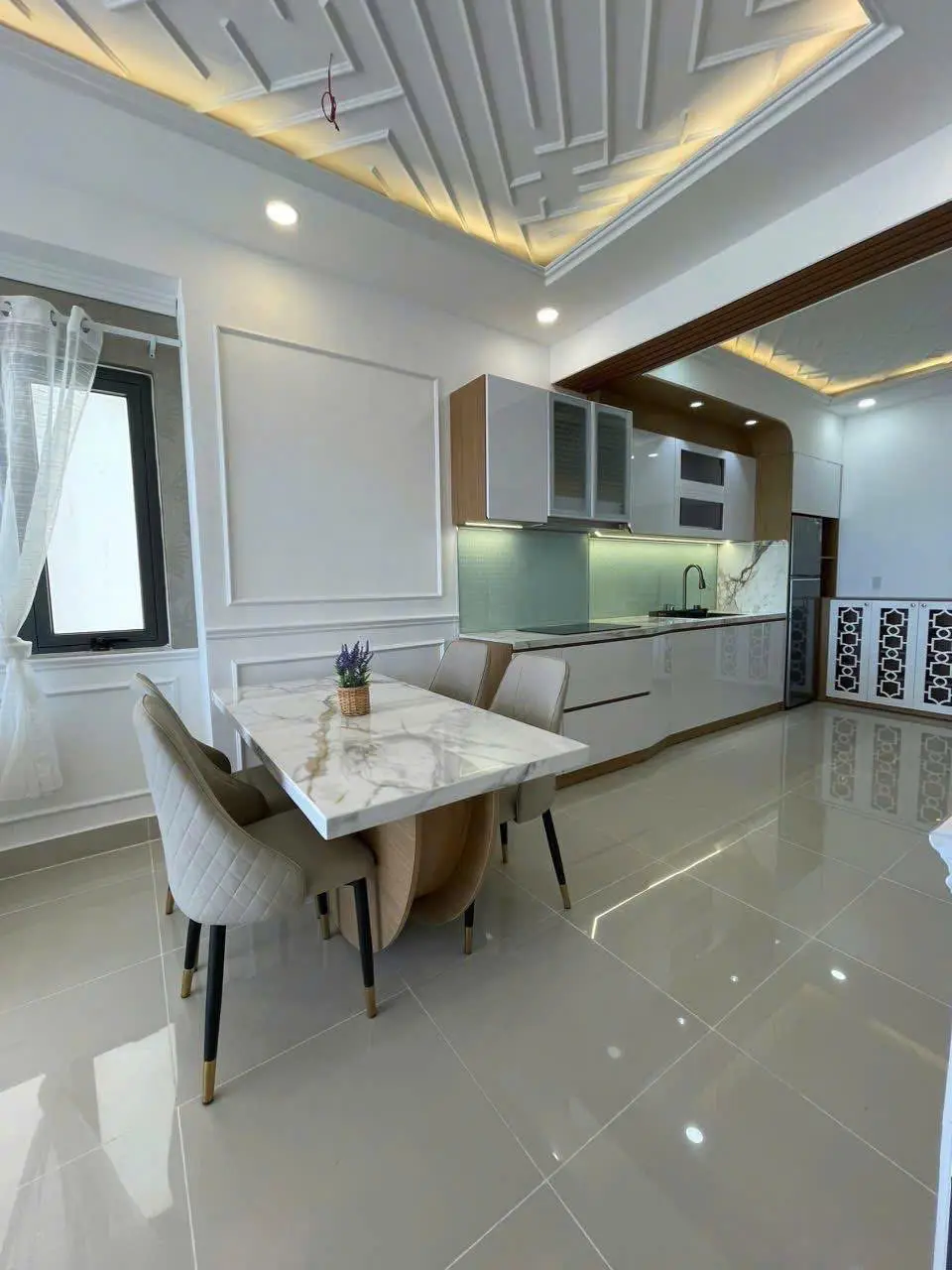 Bright apartment interior with a marble dining table, white cabinets and a kitchen