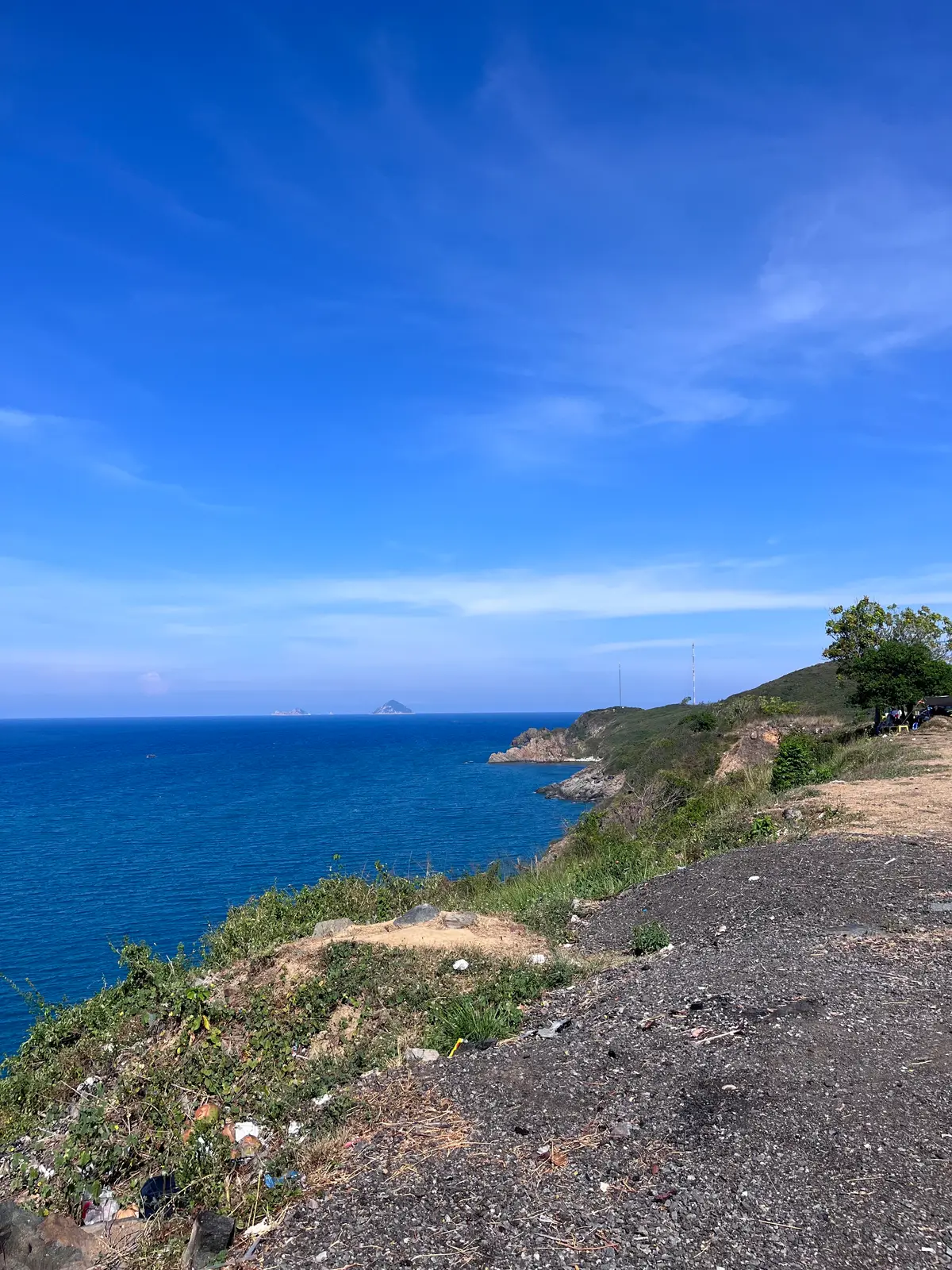 Blue bay and rocky headland seen from a coastal road viewpoint