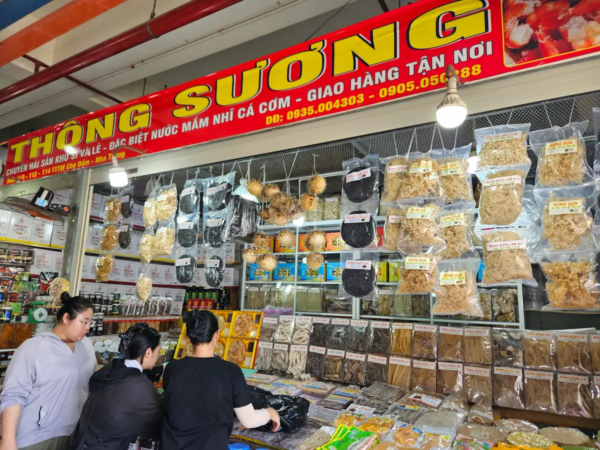 Dried fruit and seafood snack stall with packed bags on the shelves and shoppers at the counter