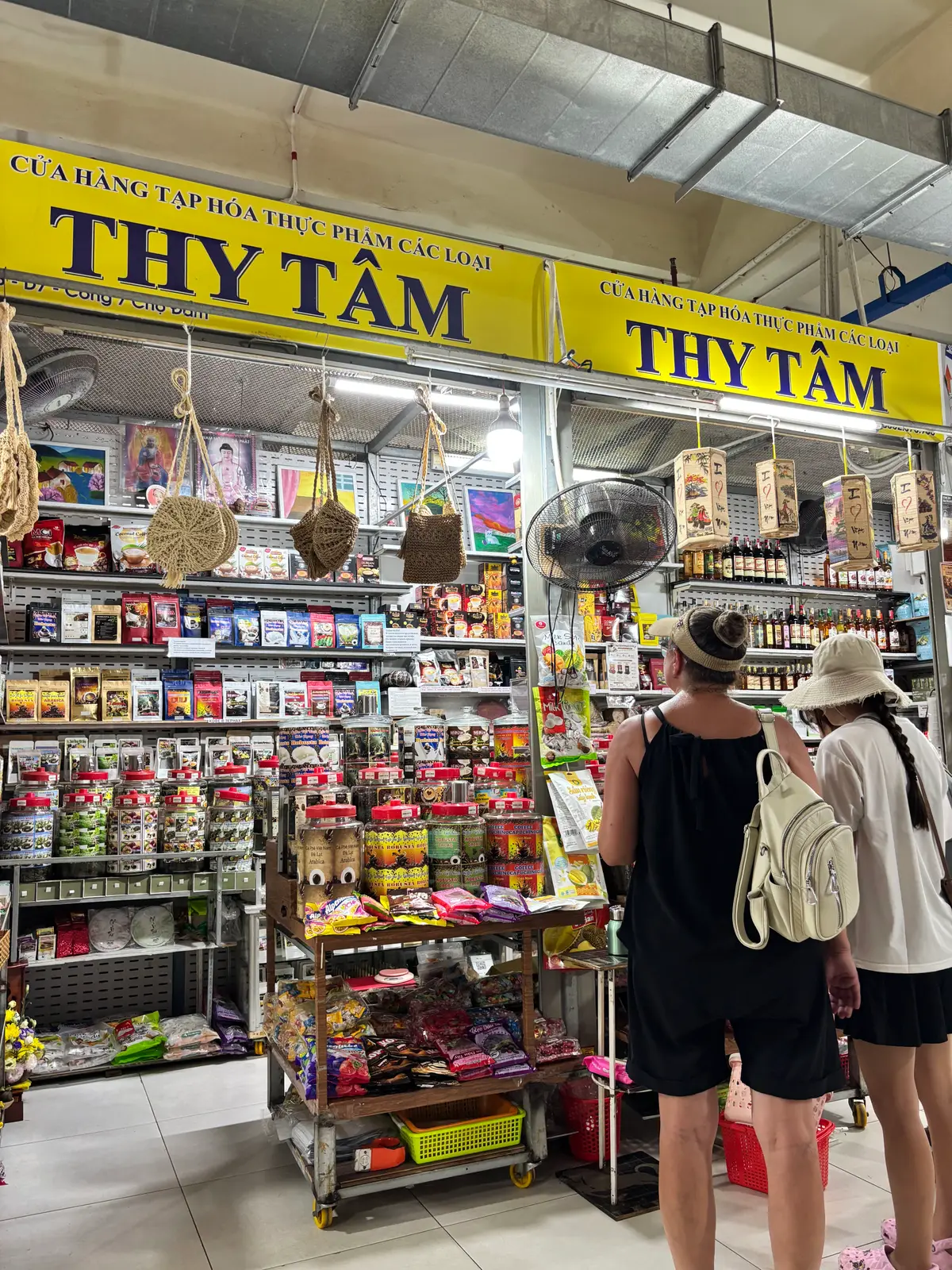 Shelves of souvenirs, woven bags and bottled sauces at a market stall