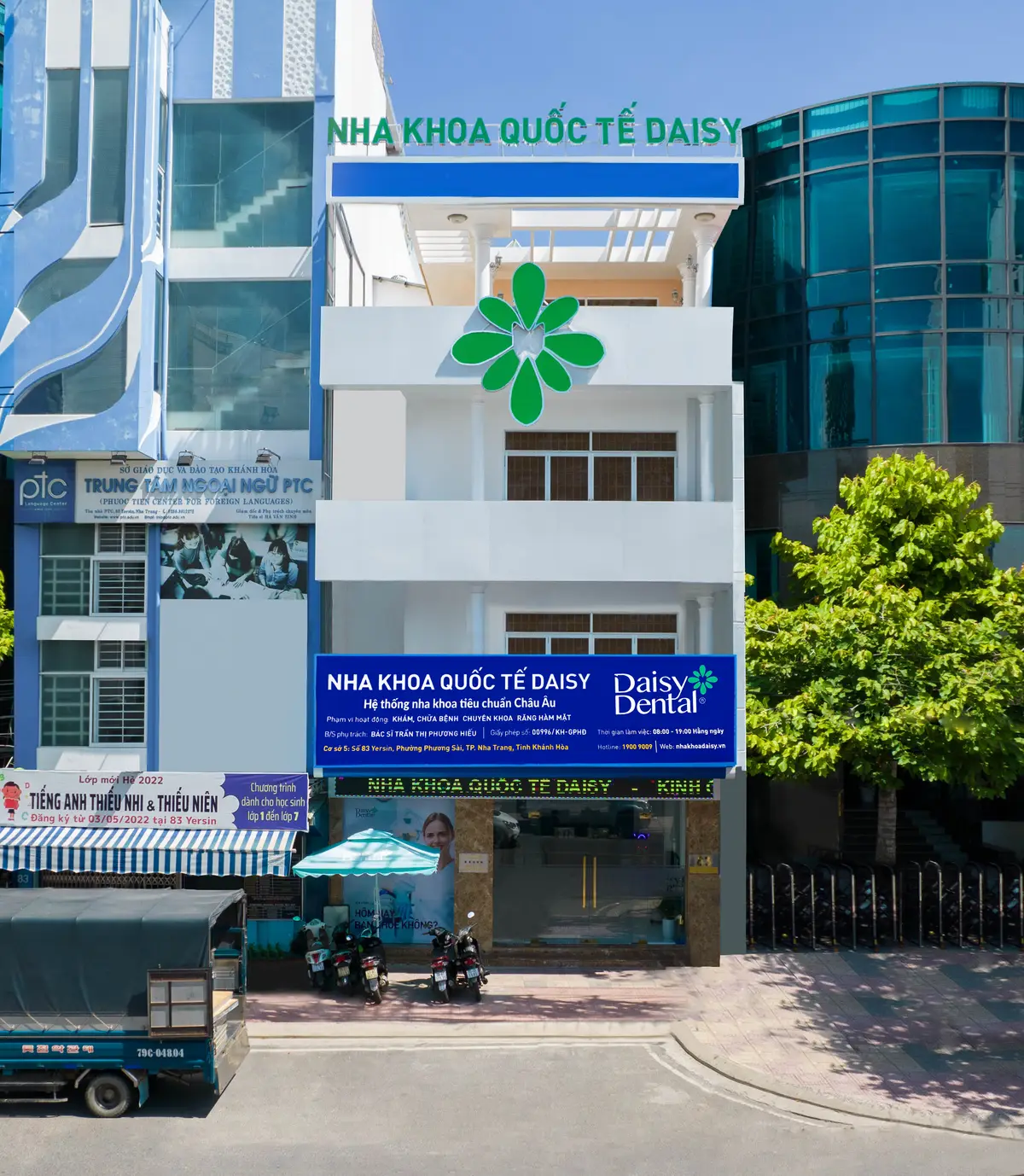Narrow white clinic building with a green flower logo and a blue DAISY sign
