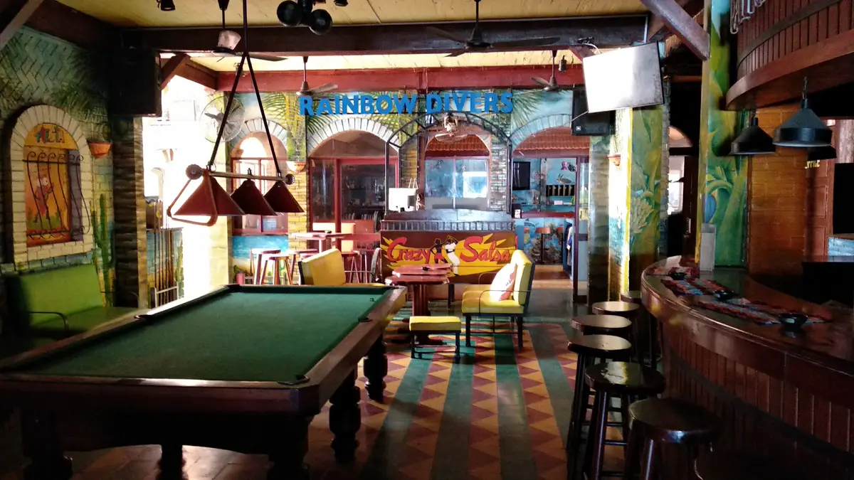 Bar with a pool table, stools and a mural wall inside the dive centre building