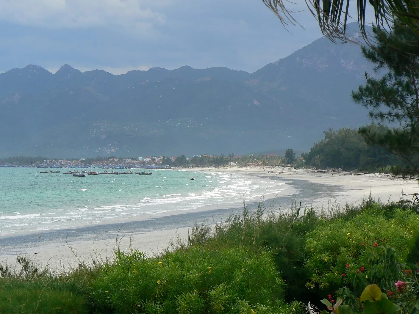 Curving white sand beach with turquoise water and mountains behind