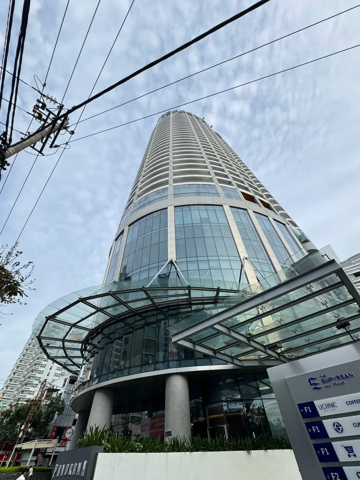 Looking up at the glass-fronted tower of an apartment and hotel building in central Nha Trang with a glass canopy at its base