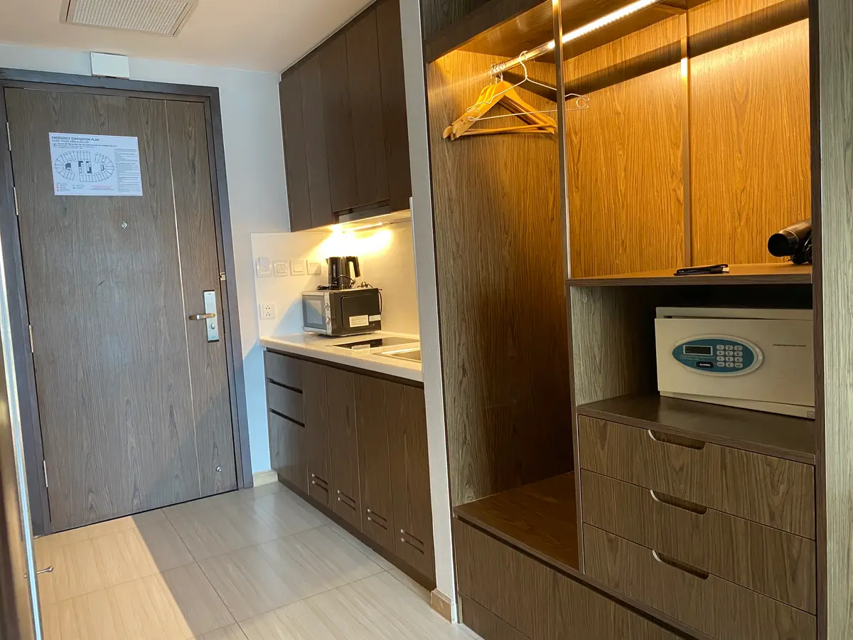 Inside a furnished apartment with a small kitchenette, a wooden wardrobe, a safe and the entrance door