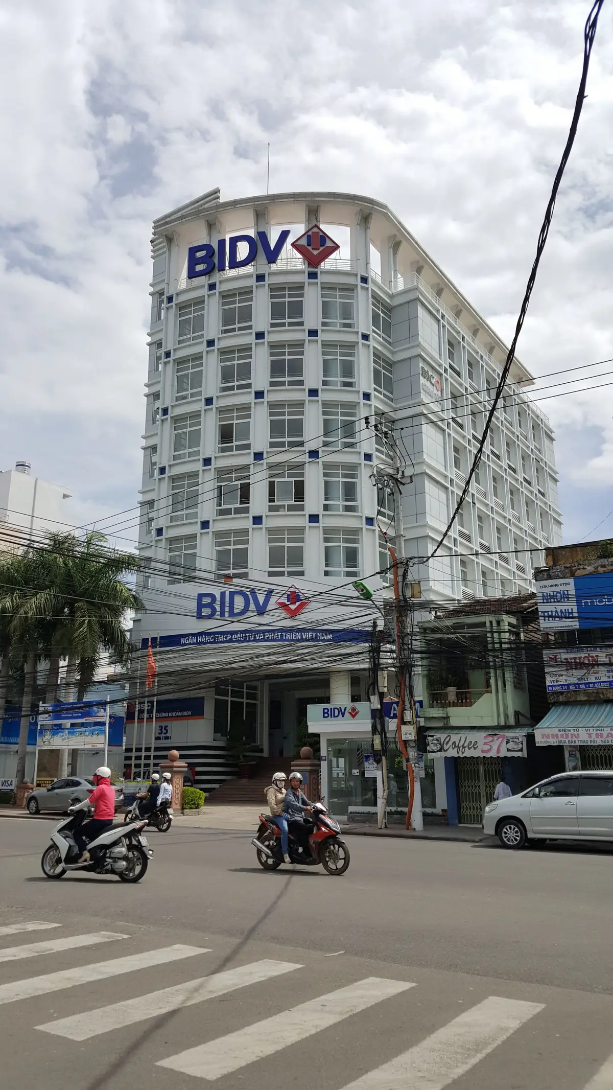 Street view of a white multi-storey BIDV bank building in Nha Trang with the blue bank sign above the ground floor