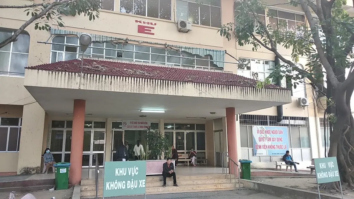 Low yellow hospital building with a covered entrance and a no-parking area sign