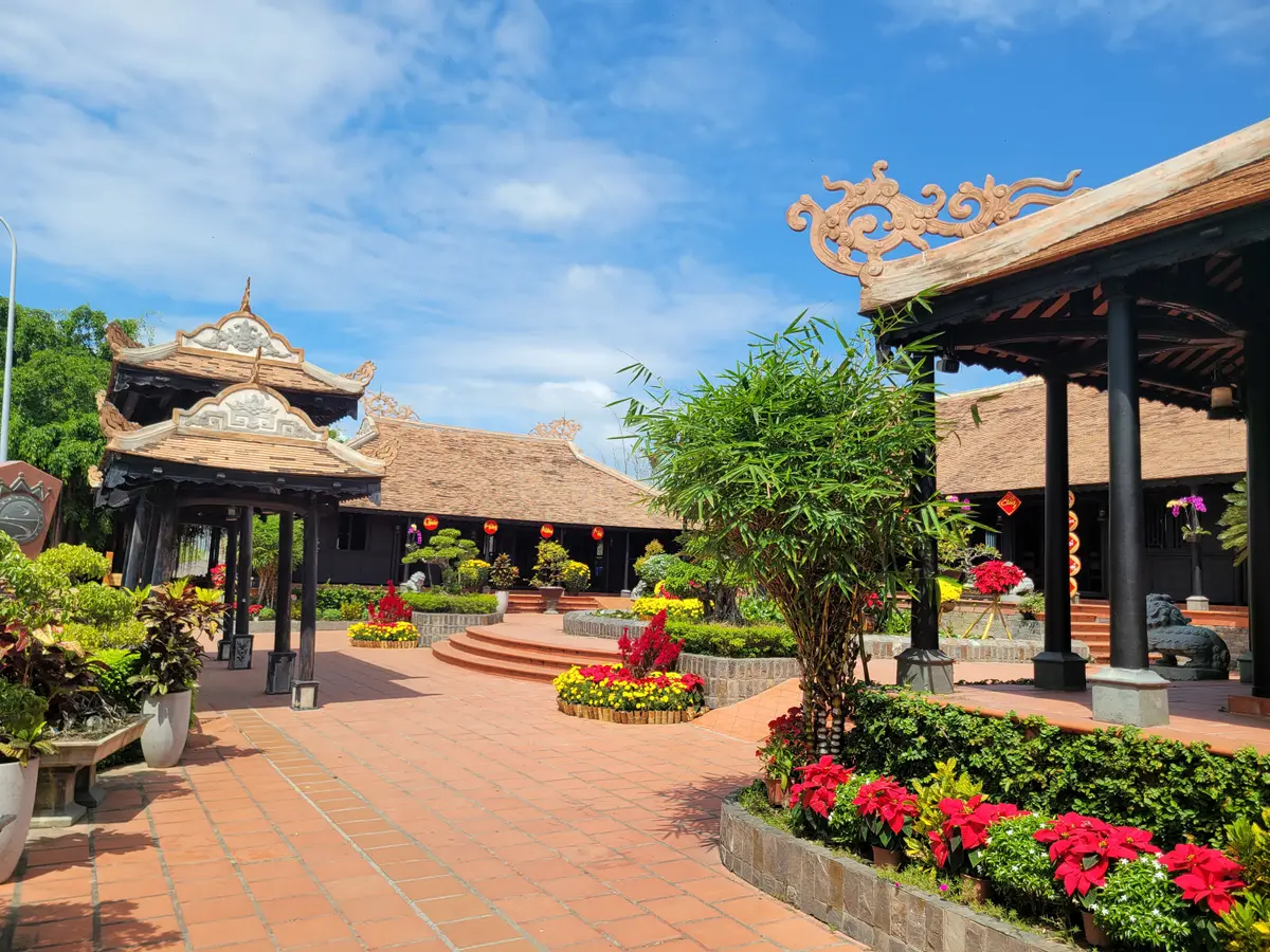 Wooden roofed pavilions around a brick courtyard planted with red flowers