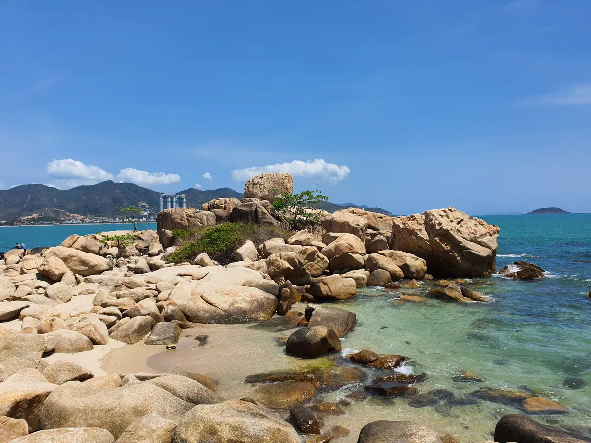 Rocky cove with scattered boulders and clear water beneath a blue sky