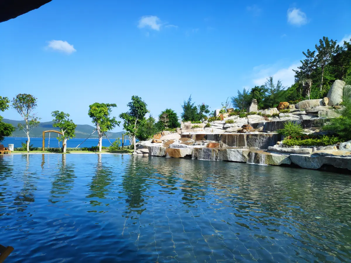 Large infinity pool with a rocky waterfall feature and the bay beyond