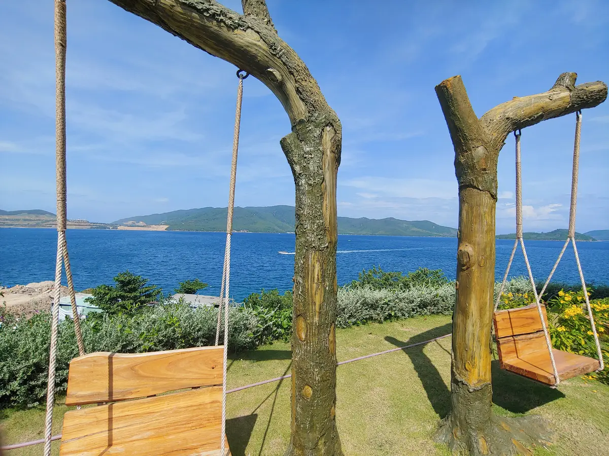 Two wooden posts holding swings facing the bay