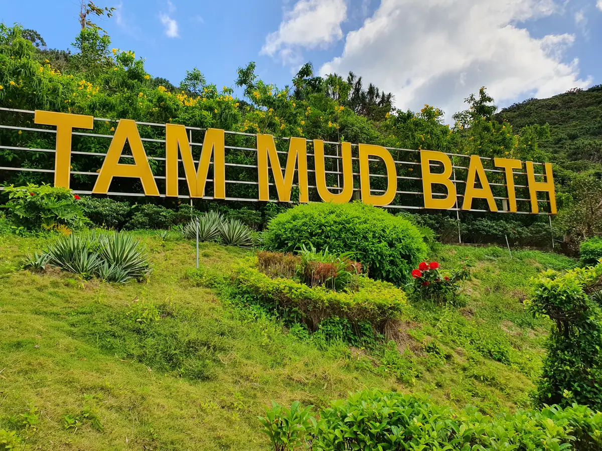 Yellow letters spelling Tam Mud Bath on a green hillside