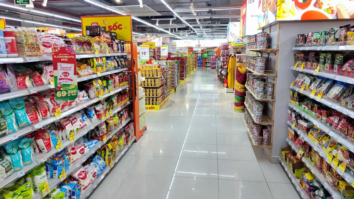 Bright supermarket aisle with shelves on both sides and a tiled floor