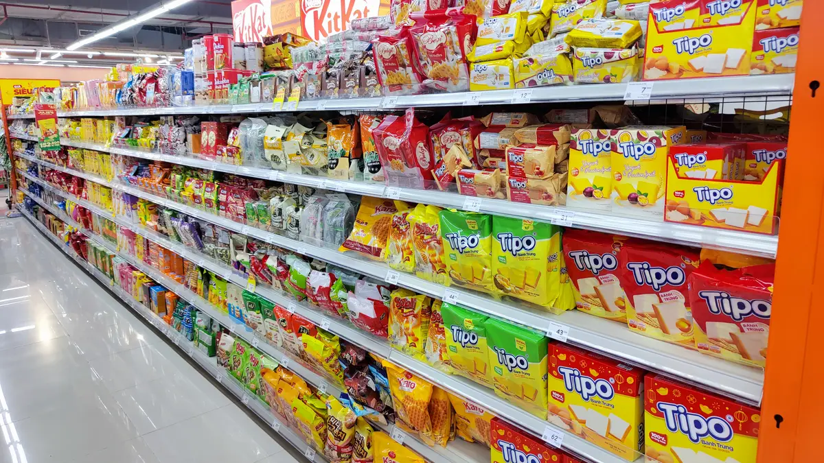 Long supermarket aisle of snack packs with biscuits in yellow packaging