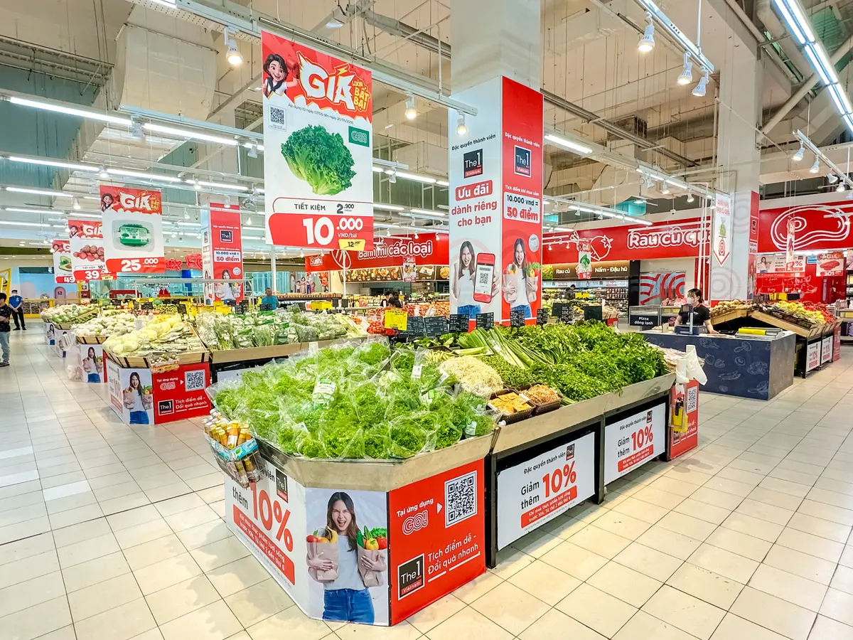 Wide supermarket produce hall with leafy greens on central display tables