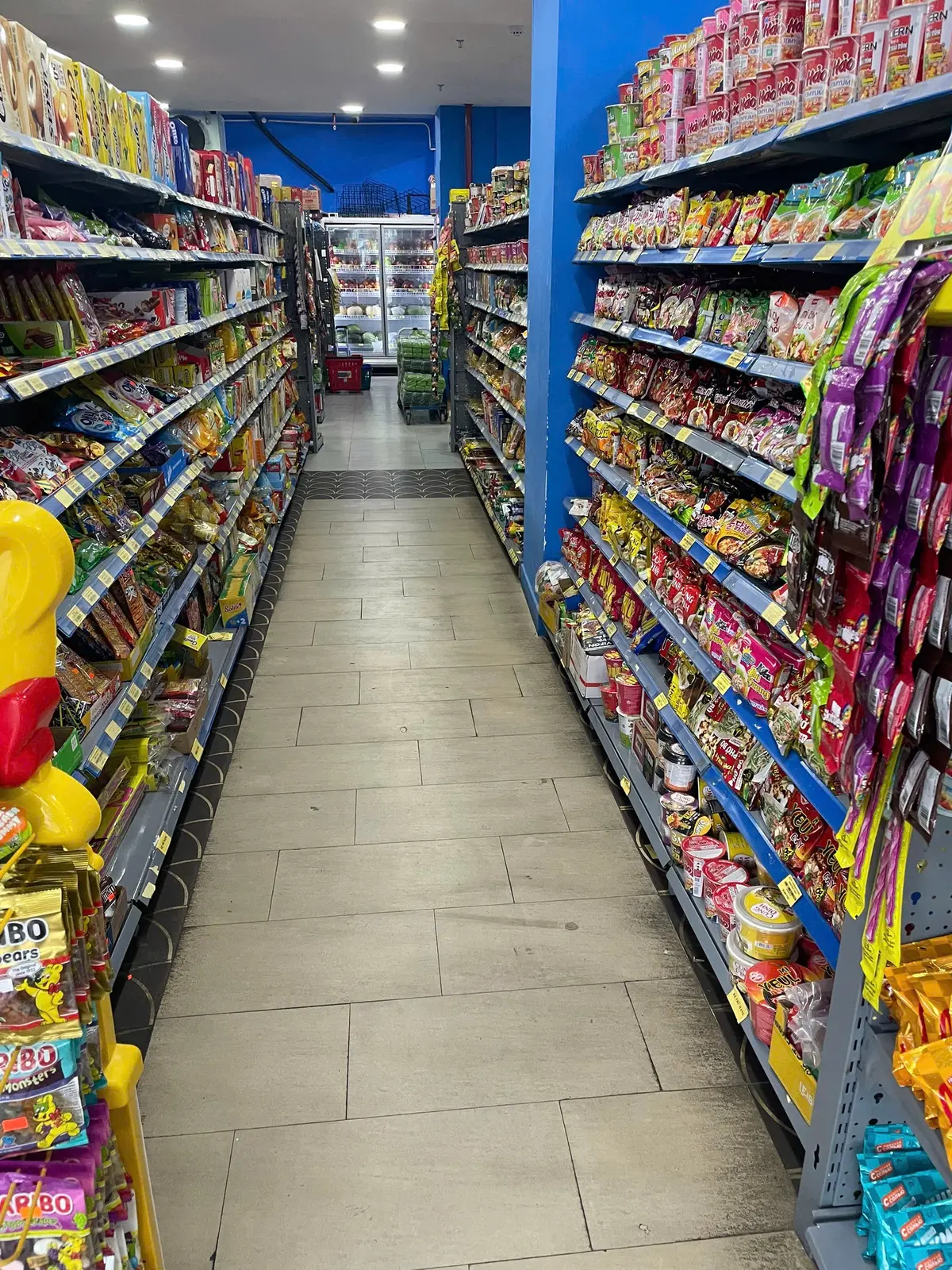 Narrow supermarket aisle with packaged snacks on shelves on both sides