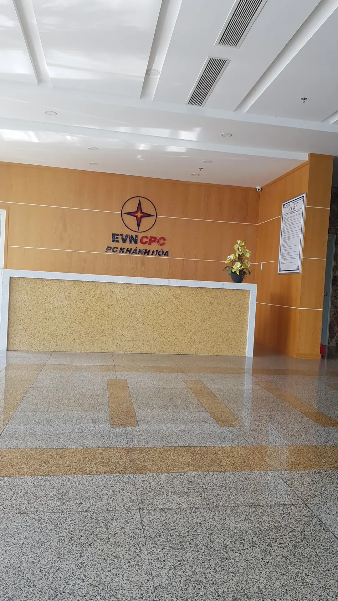 Reception desk of the power company with its logo on a wood-panelled wall above the counter.