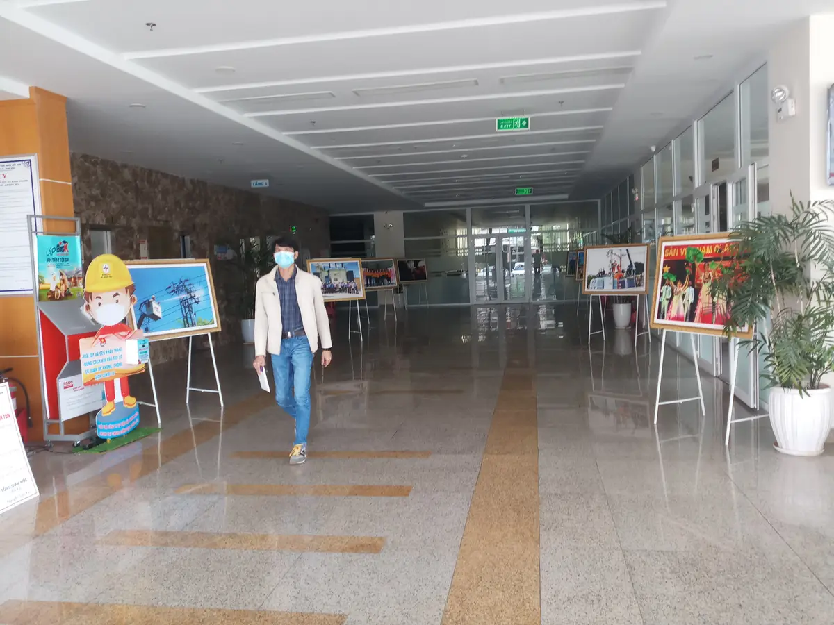 Wide ground-floor hall of the power company with display boards along the walls and a visitor walking in.