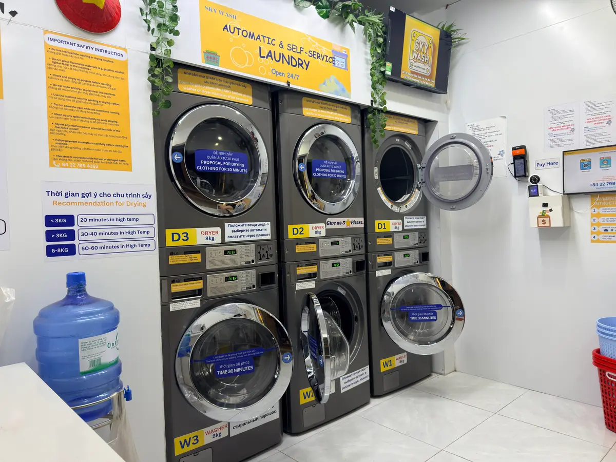 Stacked industrial washers and dryers with instructions on the wall in a self-service laundromat
