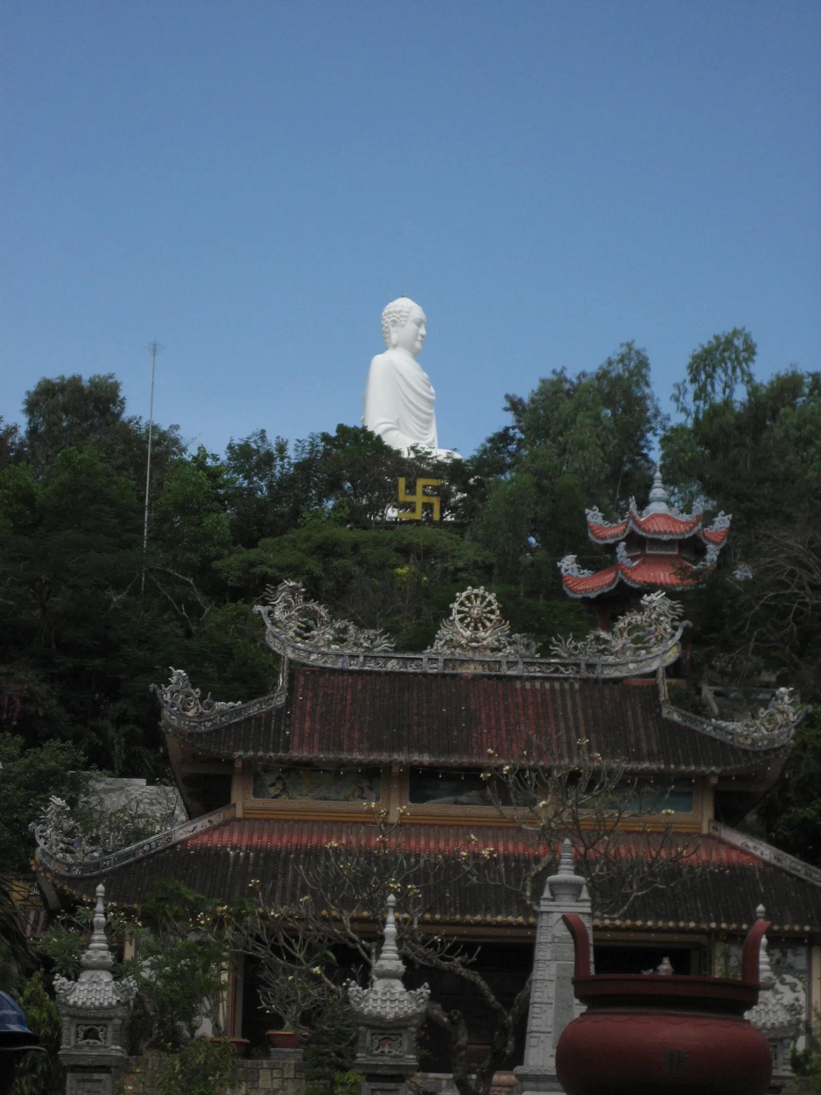 White seated Buddha statue on a hillside above Long Son Pagoda