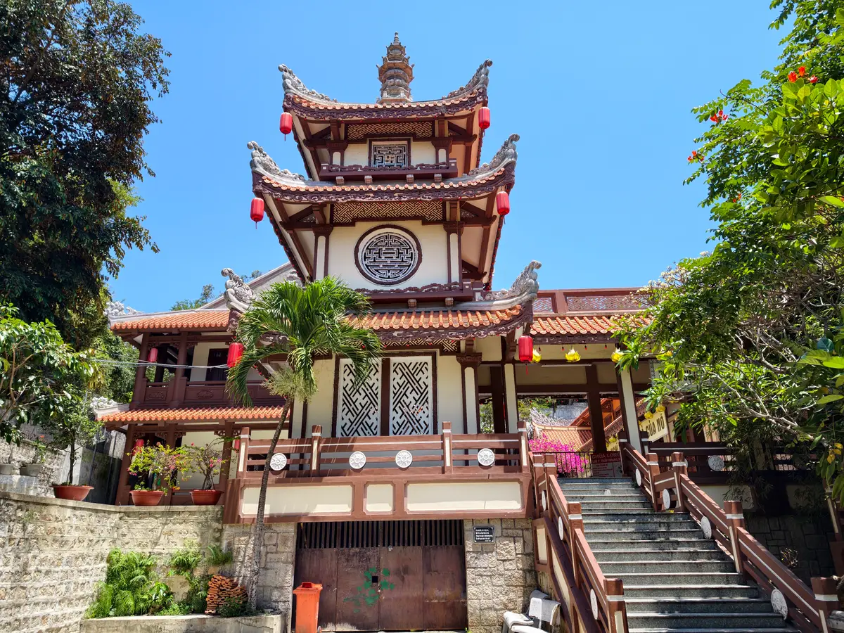 Multi-tier tower with round window and red lanterns above a stone staircase