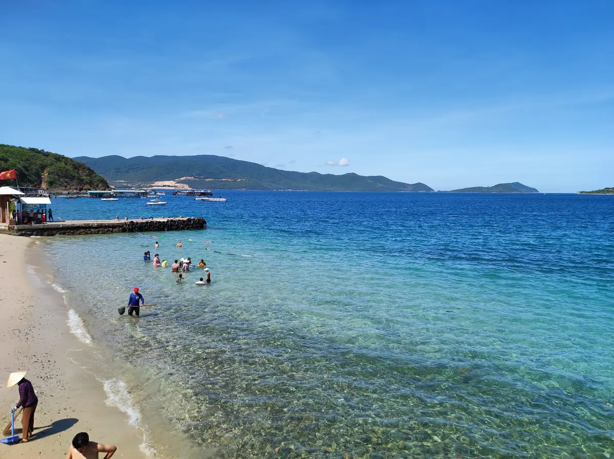 Small wooden jetty beside a white sand beach with calm blue water