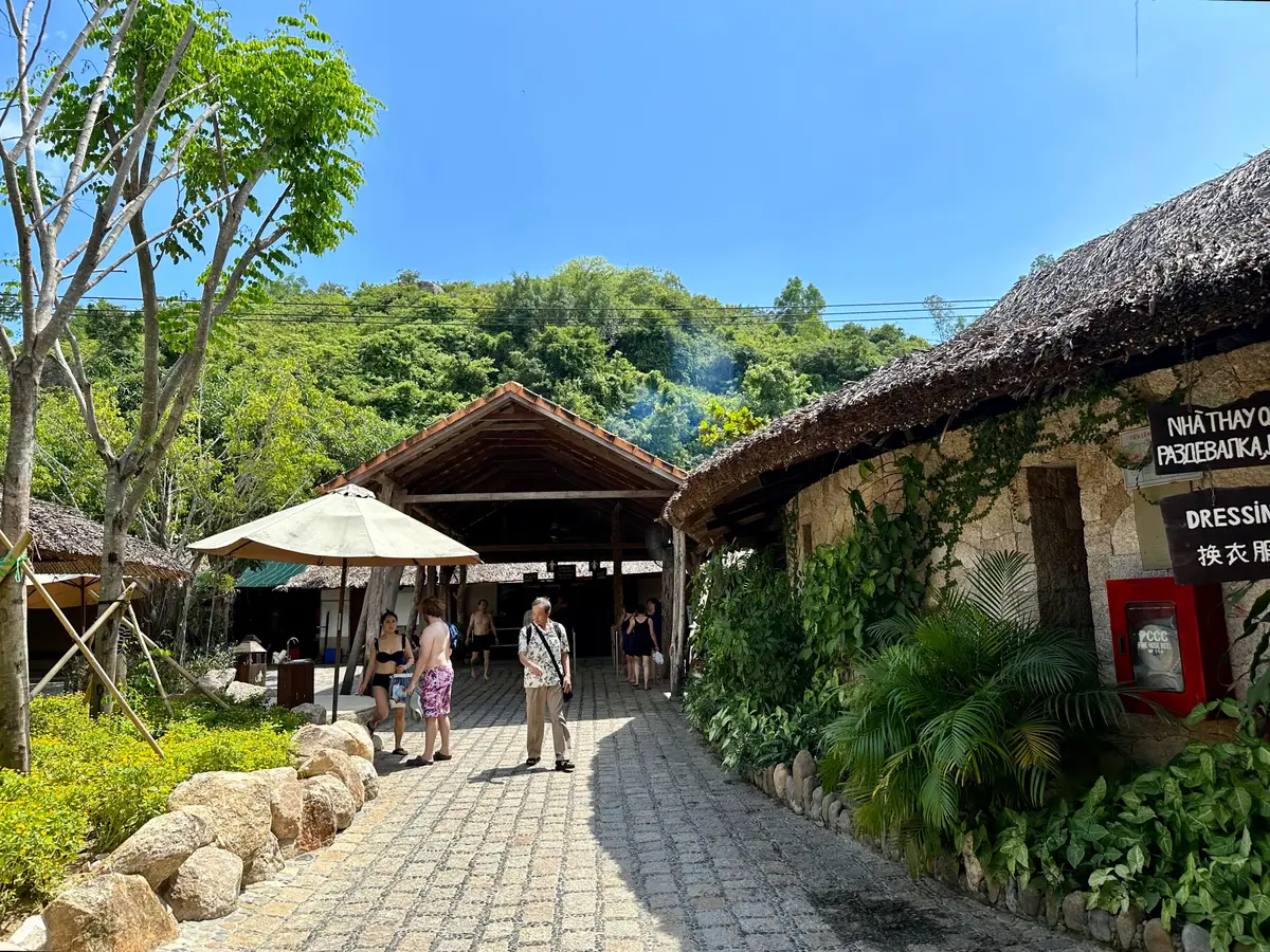 Stone paved path under a thatched gate between trees at I-Resort