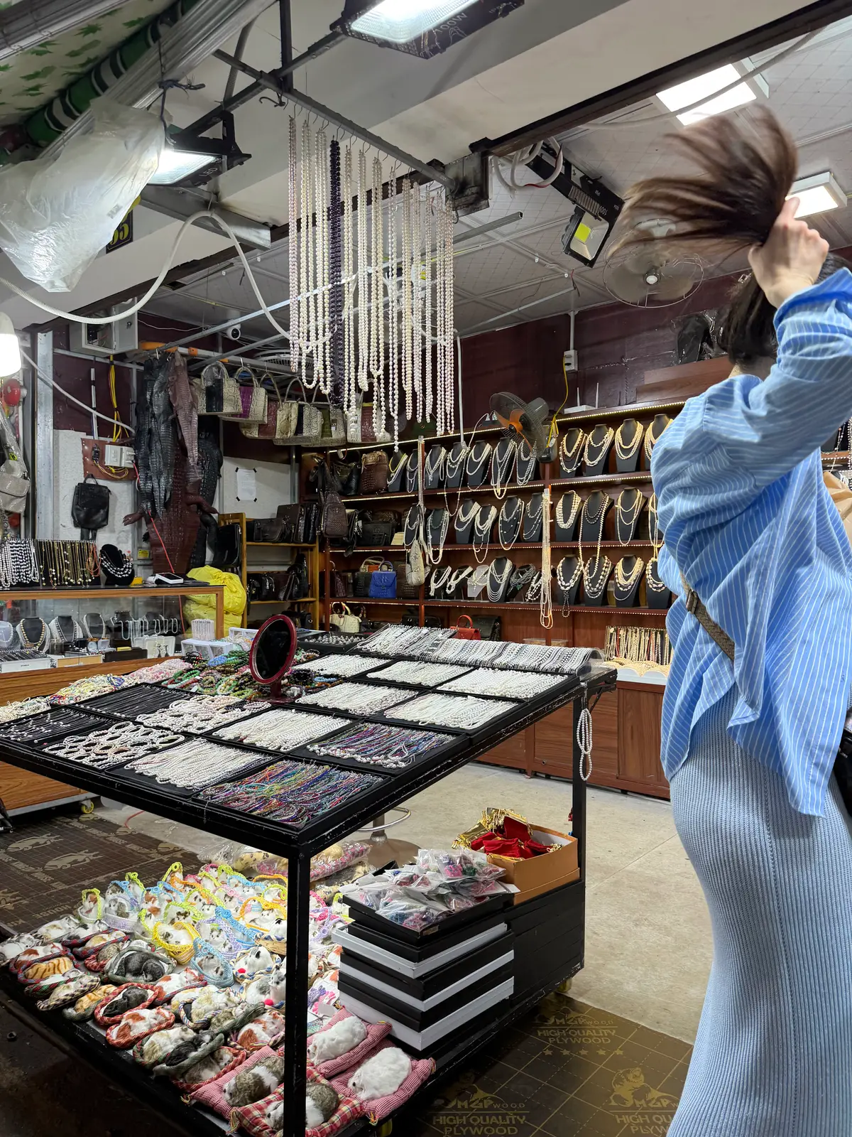 Glass counter of jewellery trays with shelves of shell goods behind
