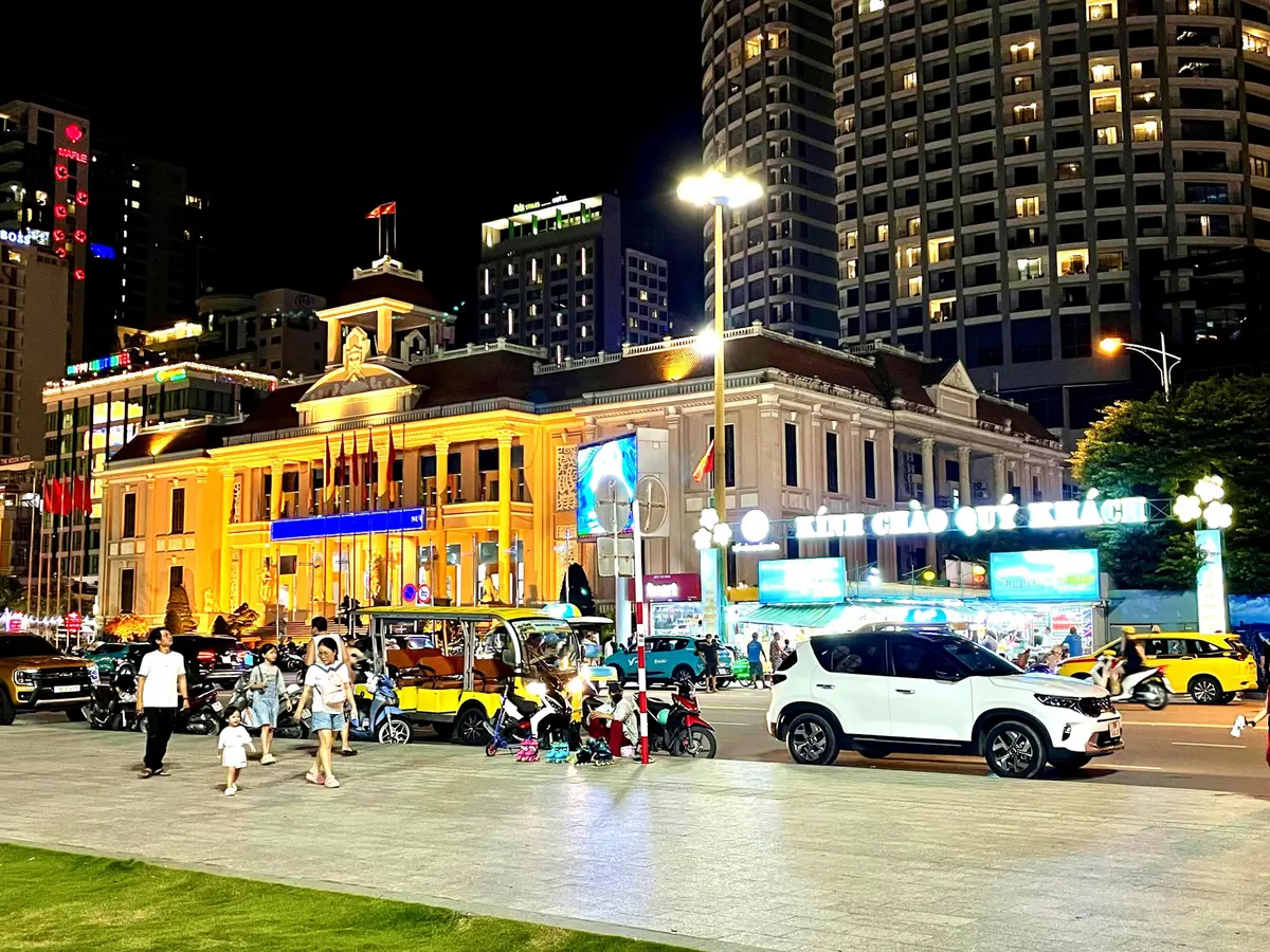 Yellow-lit colonial-style building at night beside a wide street