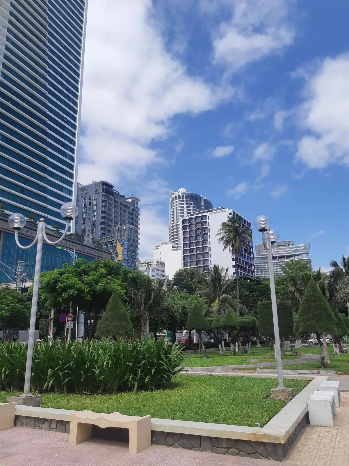 Hotel towers, street lamps and palm trees along the Nha Trang seafront under a blue sky