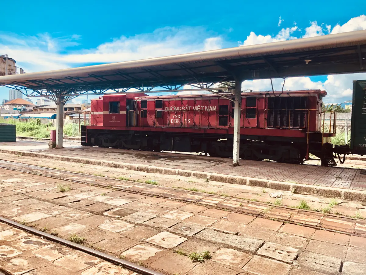 Red diesel locomotive standing at a platform under a long canopy