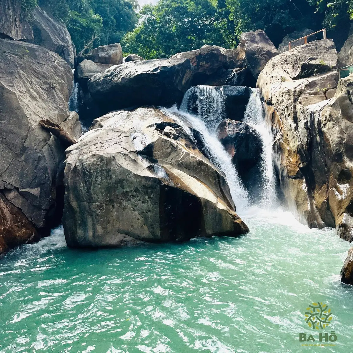 Small waterfall pouring over large rocks into a turquoise pool