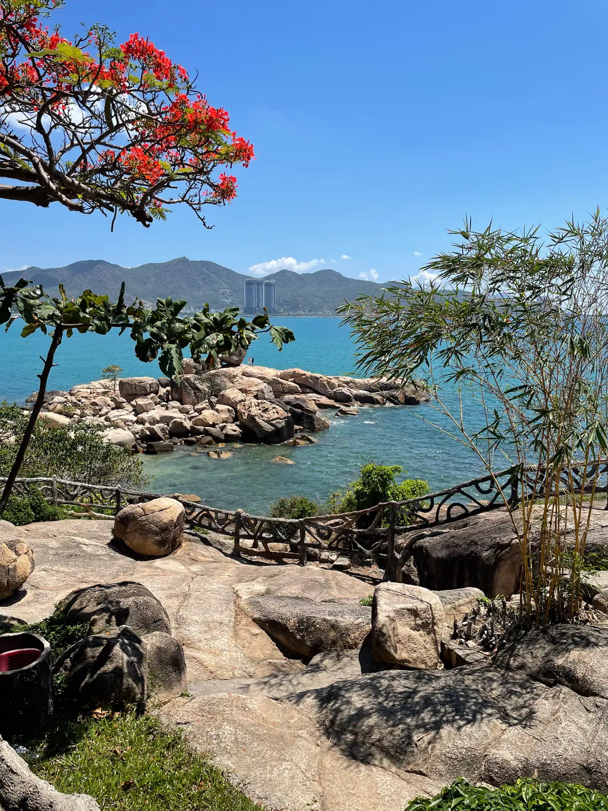Rocky headland path with a wooden railing above turquoise water