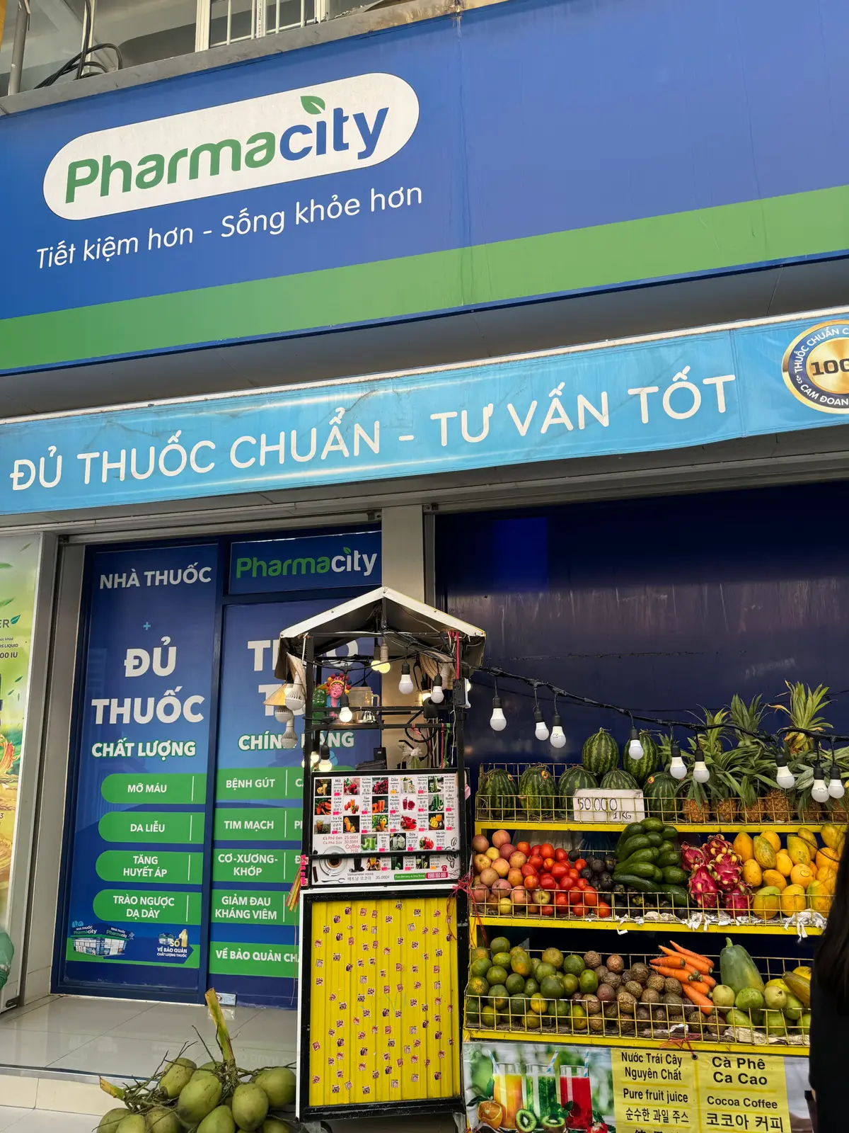 Pharmacity shopfront with a blue banner and a fruit display outside