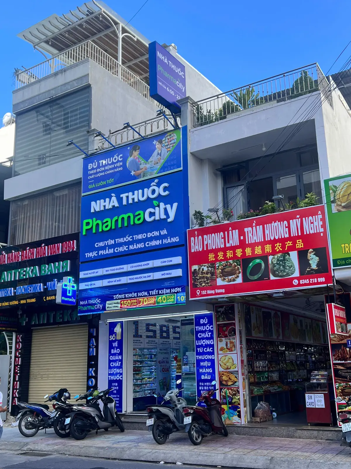 Blue and green Pharmacity sign on a narrow street building