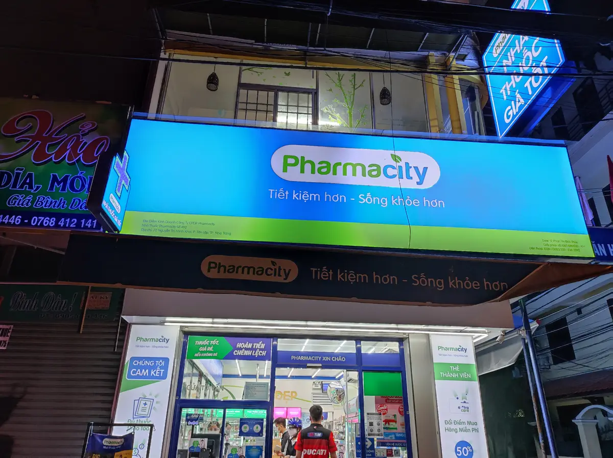 Green Pharmacity shop sign over a lit shopfront at night