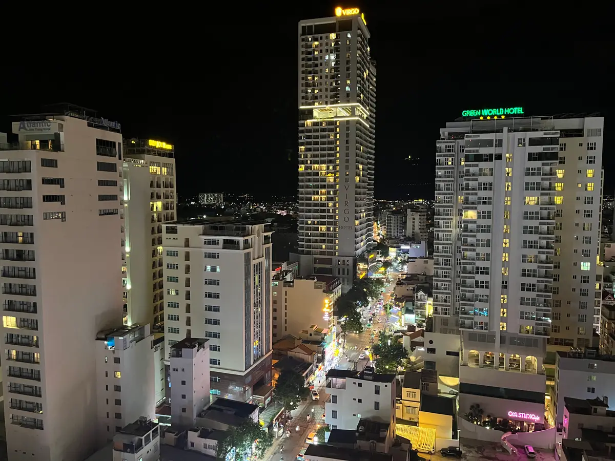 Night view of lit apartment and hotel towers along a street in Nha Trang