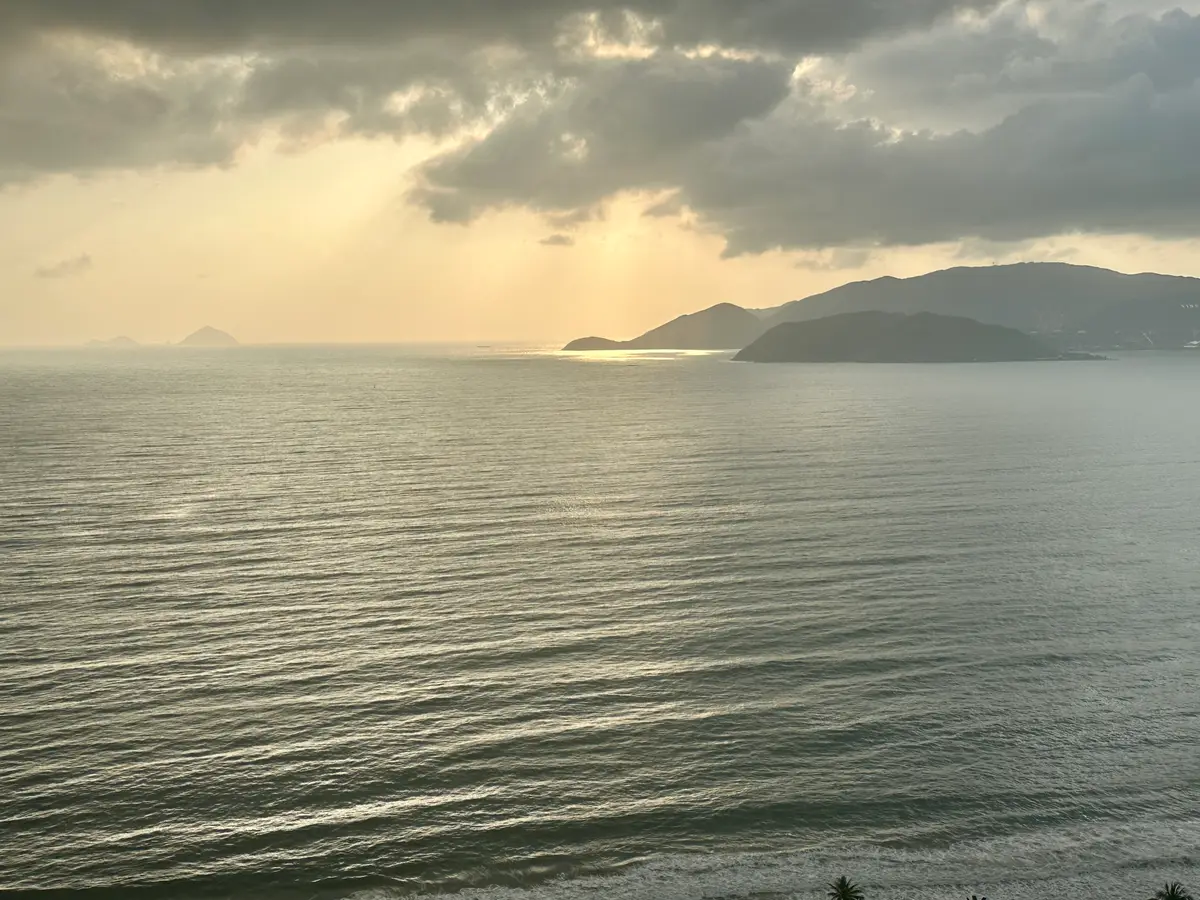 Calm sea at sunset under a cloudy sky with a headland on the right