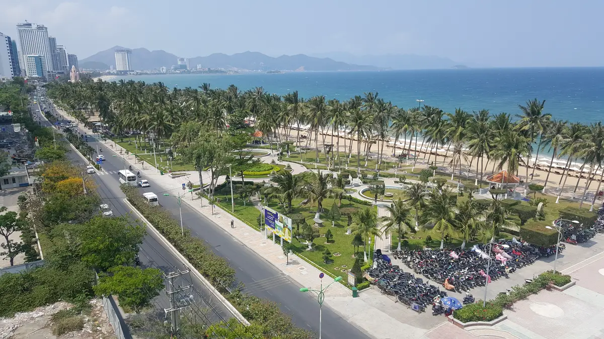 Aerial view of the seafront road and park in Nha Trang with rows of parked motorbikes beside the road and a paved square