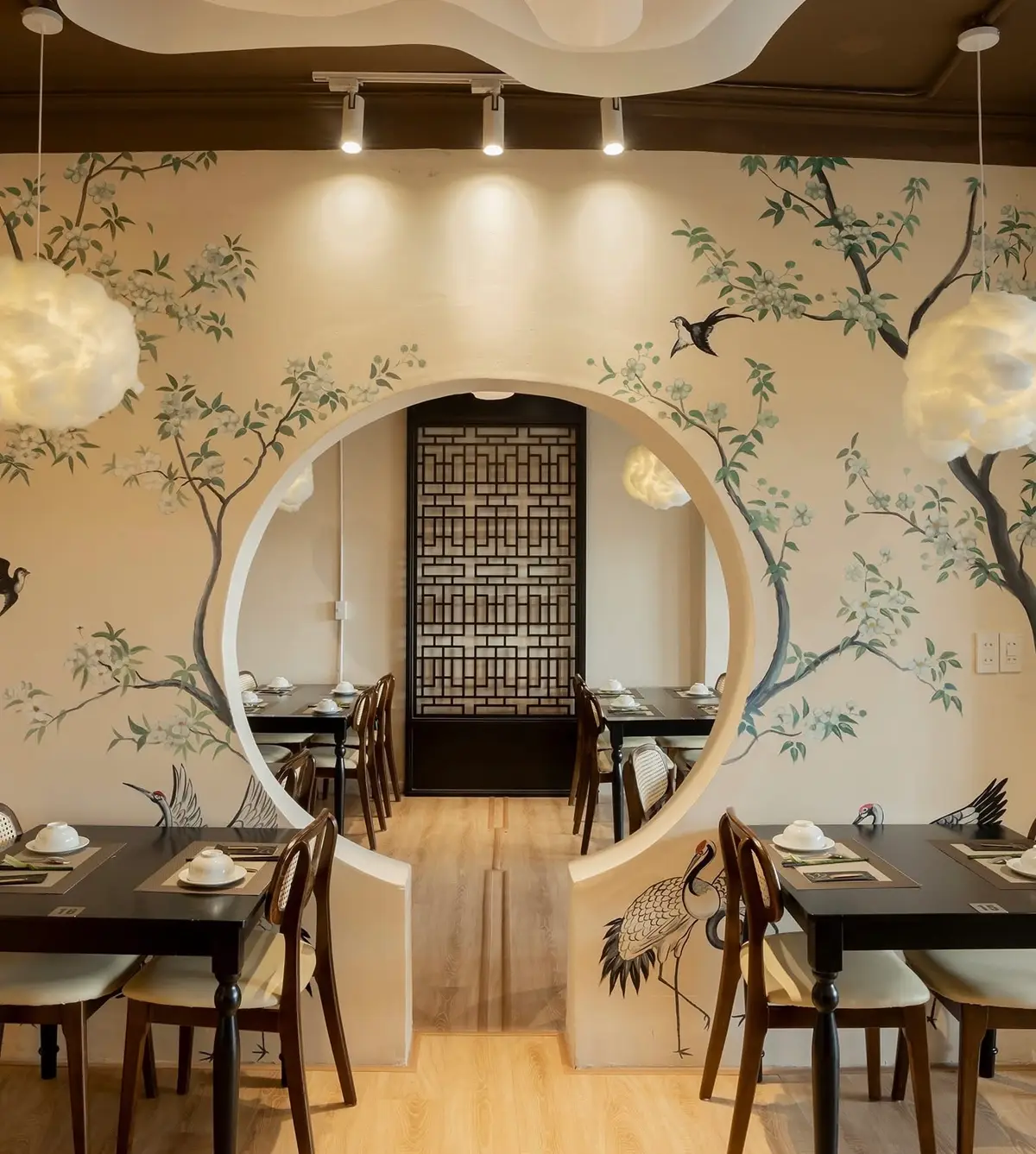 Round moon-gate doorway painted with birds and branches in a quiet dining room