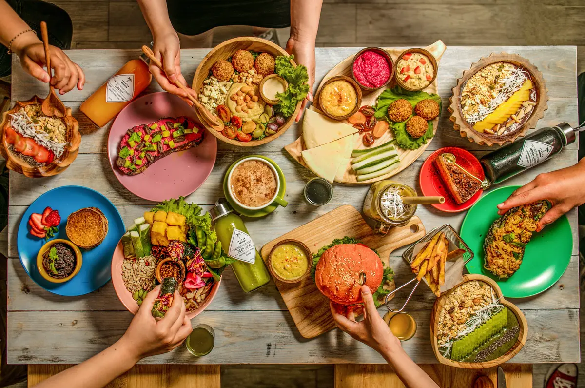 Table covered with colourful plant-based dishes, bowls and drinks seen from above