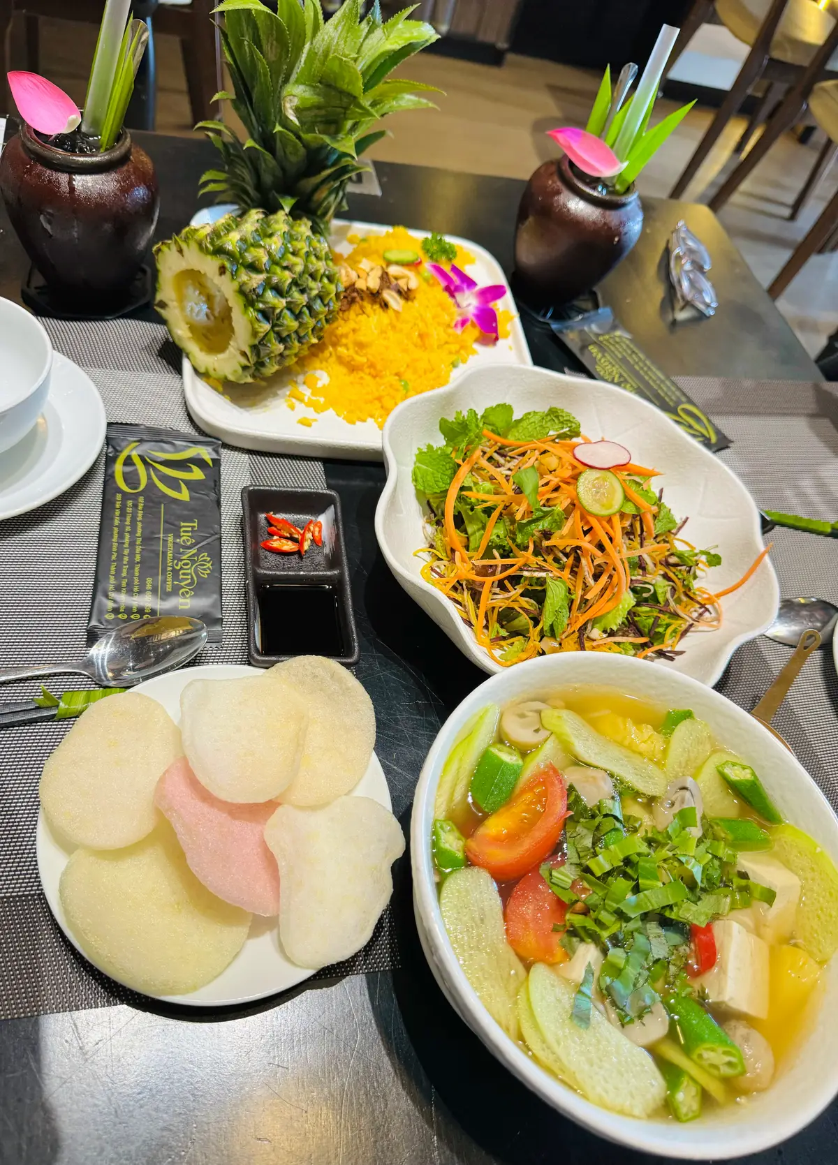 Table of vegetarian dishes with rice crackers, a leafy salad and a bowl of soup
