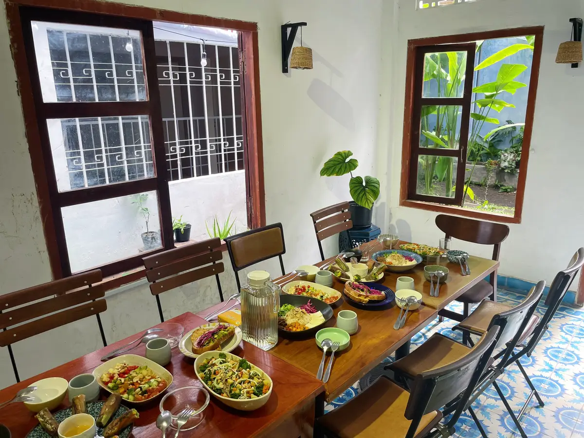 Dining table set with several salad bowls beside a window with shutters