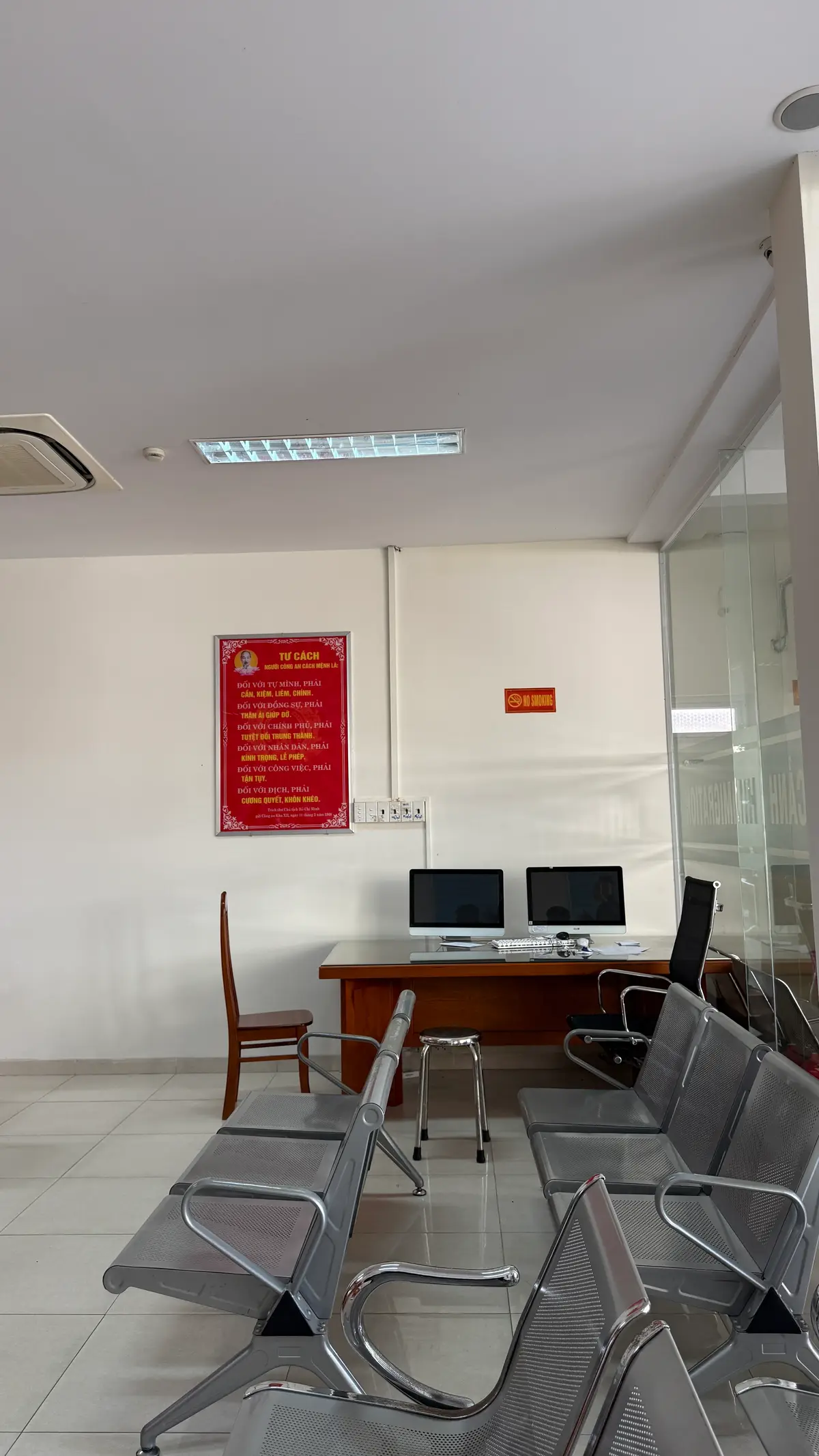 Small room inside the office with a wooden desk, two computer monitors, an office chair and a red notice board on the wall.