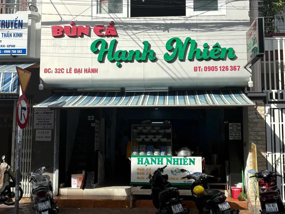 Shopfront with a green and red sign reading bun ca Hanh Nhien